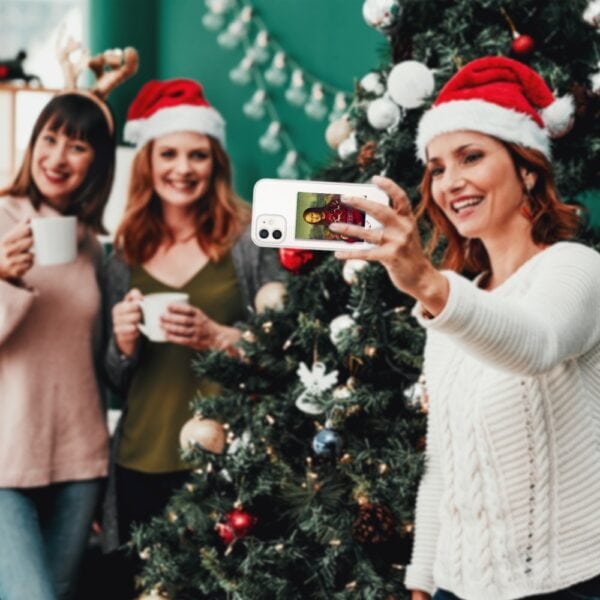 Przyjaciele robią selfie przy choince, świąteczne czapki.