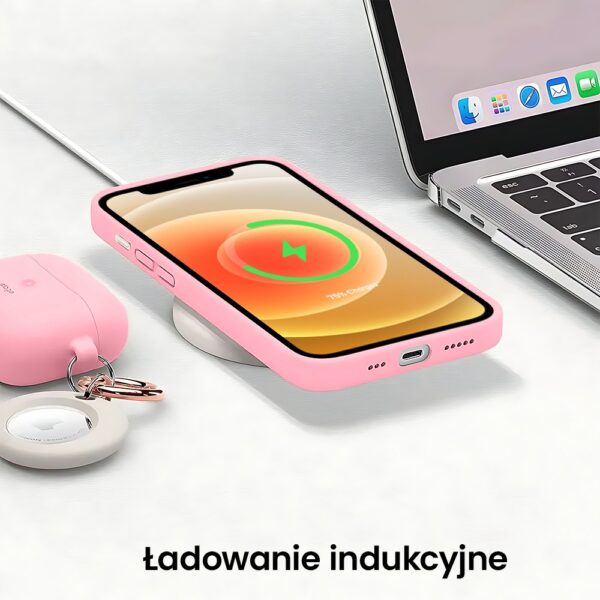 Telefon naładowany bezprzewodowo obok laptopa i kluczy.