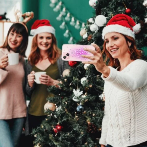 Etui do iPhone 13 malowana choinka na różowym świetle, przeźroczyste (3) Przyjaciele robią selfie przy choince świątecznej.