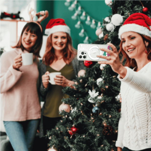 Kobiety robią selfie przy choince, świąteczne czapki.