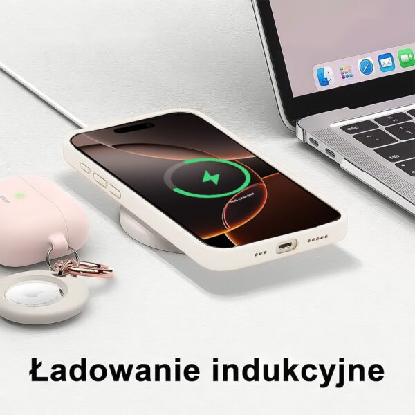 Smartfon ładujący się indukcyjnie obok laptopa.