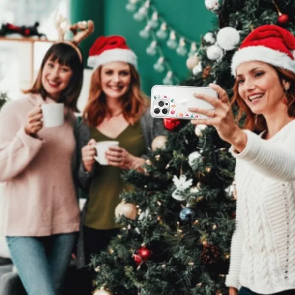 Przyjaciele robią selfie obok choinki.