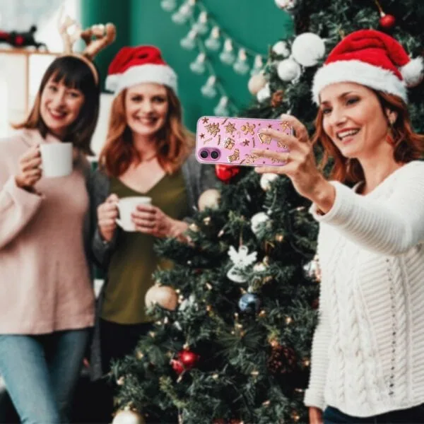 Etui do iPhone 16, magia pierniczków, przeźroczyste (2) Kobiety robią selfie przy choince świątecznej.